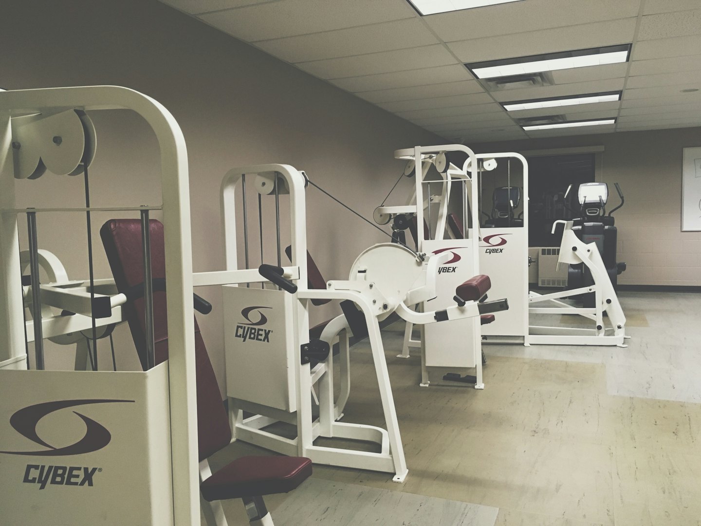 Moderne attrezzature da palestra con telaio bianco e rivestimenti bordeaux in una sala fitness.