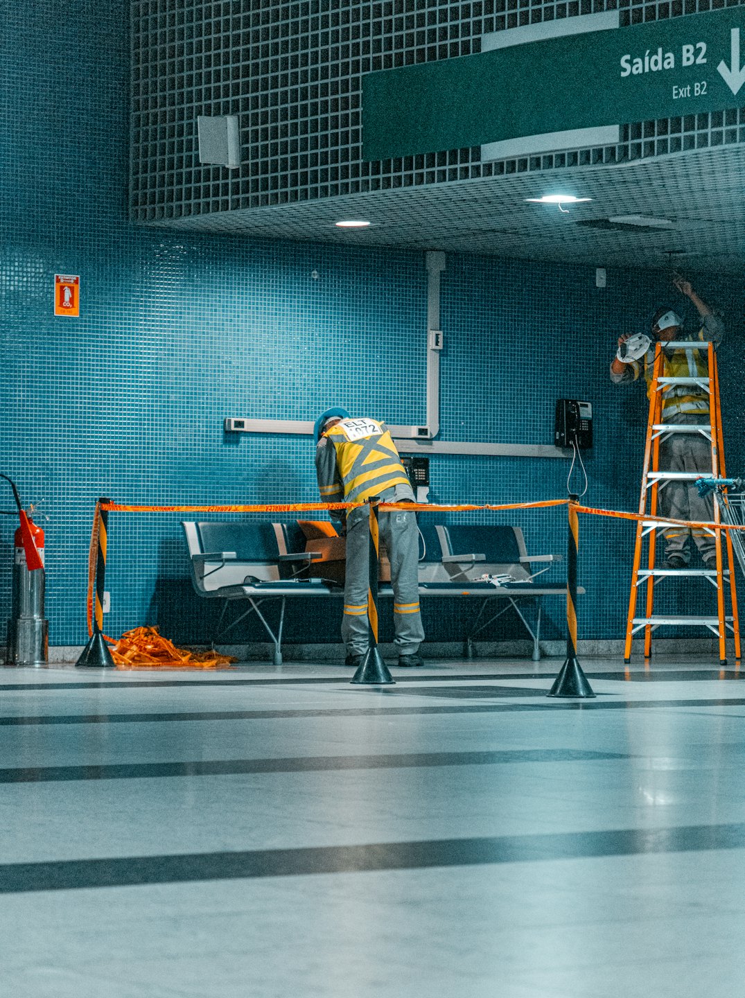 Operai con dispositivi di sicurezza che mantengono gli infissi in un edificio pubblico piastrellato.