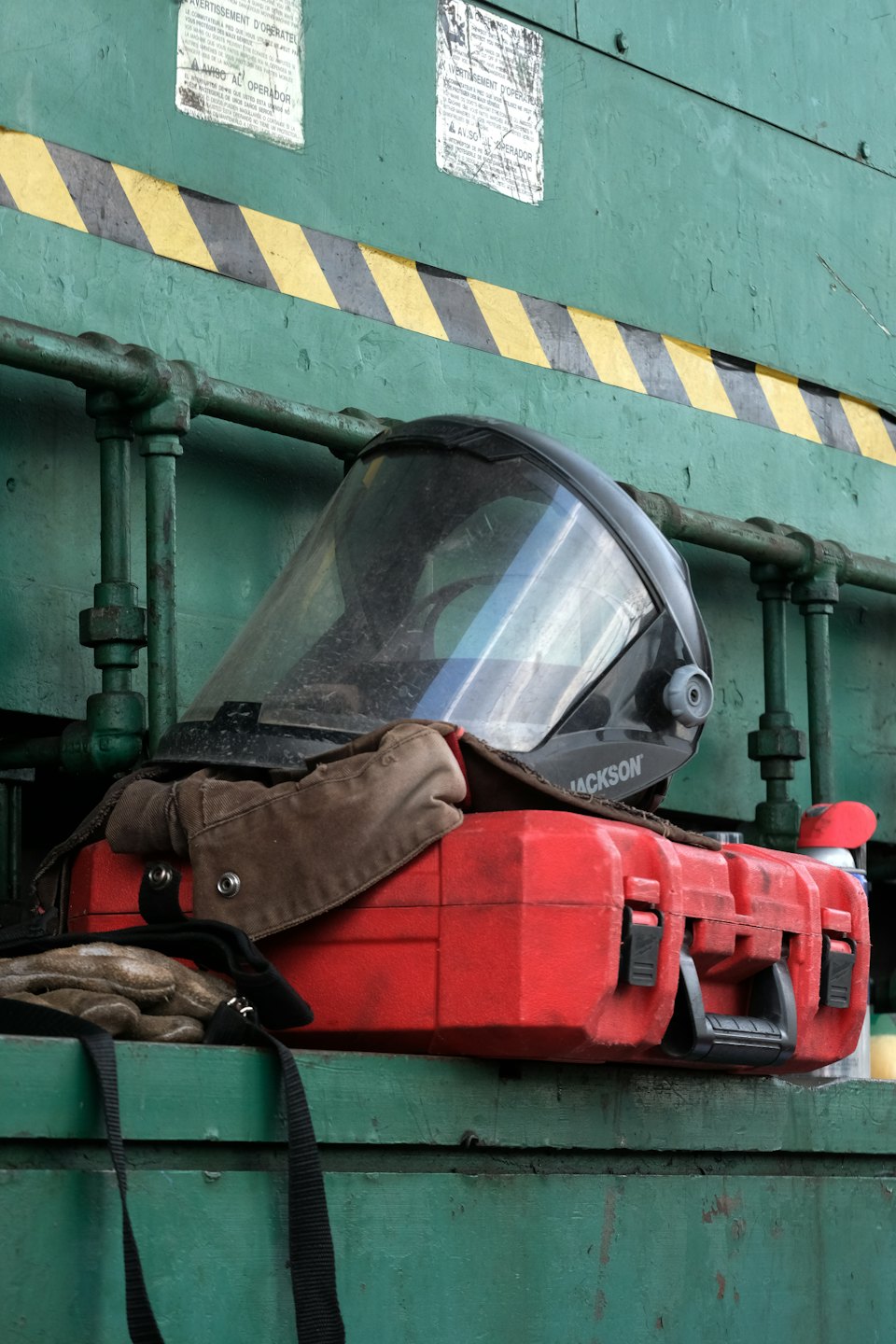 Casco protettivo e guanti da lavoro appoggiati su una cassetta degli attrezzi rossa.